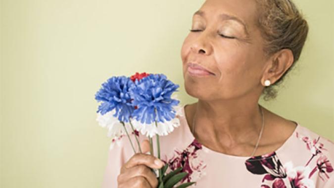 Mujer adulta ayor oliendo flores